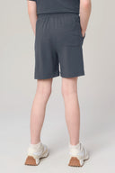 Girl wearing granite gray athletic shorts with pocket, white sneakers, and socks, rear view.
