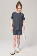 Girl wearing granite gray athleisure shorts and t-shirt set, holding a water bottle