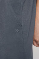 Close-up of grey athletic shorts with side pocket and small geometric logo detail.