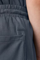 Close-up of gray elastic waist activewear shorts with pocket and visible logo patch