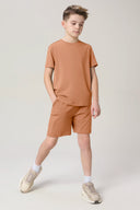 Boy wearing mocha brown activewear shorts and t-shirt set, neutral background
