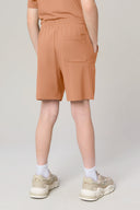 Boy wearing mocha brown athletic shorts with elastic waistband and back pocket, rear view