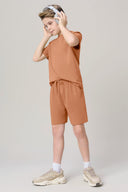 Boy wearing mocha brown athletic shorts and matching t-shirt, listening to headphones