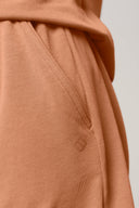 Close-up of mocha brown athleisure shorts pocket with stitched detail and small logo