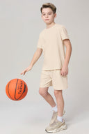 Boy in sand-colored shorts and t-shirt playing basketball in athleisure sneakers