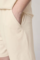 Close-up of hand-in-pocket sand beige boys' athletic shorts, soft lightweight fabric
