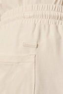 Close-up of beige elastic waistband shorts with back pocket and stitched label detail