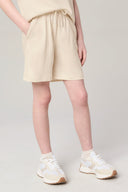 Girl wearing sand-colored athleisure shorts with drawstring waist and white sneakers