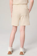 Girl wearing beige athleisure shorts with back pocket, white socks, and sneakers