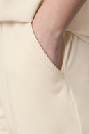 Close-up of hand in pocket of sand-colored athleisure shorts with subtle logo detail