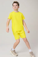 Boy modeling yellow athletic shorts and T-shirt set, summer activewear for kids
