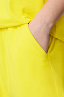 Close-up of hand in yellow athletic shorts pocket, bright activewear fabric detail