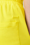 Close-up of bright yellow athletic shorts with elastic waistband and pocket detail