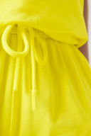 Close-up of neon yellow athleisure shorts with drawstring waist, soft fabric detail.