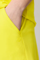 Close-up of hand in yellow athleisure shorts pocket, soft fabric, minimal design.