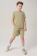 Boy wearing light olive athletic shorts and t-shirt set with chunky beige sneakers.