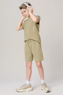 Boy wearing olive green athleisure shorts and t-shirt set, headphones, and sneakers