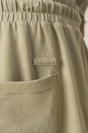 Close-up of light olive green elastic waist shorts with pocket and Seissense label