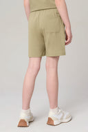 Back view of girl wearing olive green athleisure shorts with pocket, white sneakers