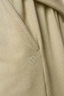 Close-up of beige athleisure shorts pocket with stitched detail and minimalist logo
