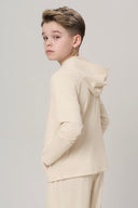 Boy wearing sand-colored kids UV hoodie and matching pants, looking over shoulder