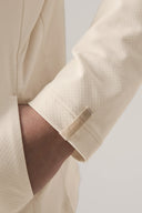 Close-up of a child's hand in the pocket of a sand-colored kids UV protective hoodie sleeve