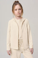 Girl wearing a sand-colored kids UV hoodie and matching lounge pants on a neutral background