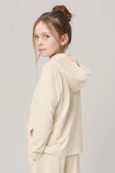 Girl wearing sand-colored kids UV hoodie and matching pants, side profile, neutral background