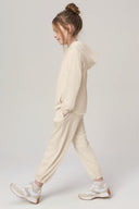 Girl in sand-colored kids UV hoodie and joggers walking, athleisure activewear outfit