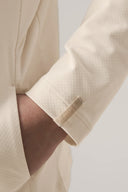 Close-up of a child's arm in a sand-colored kids UV hoodie with textured fabric and sleeve tag.