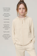 Girl wearing a sand-colored kids UV hoodie with full zip, shown with athleisure pants.