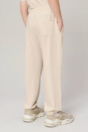 Kid wearing sand-colored jogger pants with elastic waistband and back pocket, side view