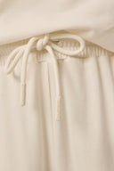 Close-up of kids sand-colored jogger pants with elastic waistband and drawstring.