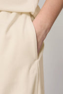 Close-up of hand in pocket of kids' sand-colored jogger pants with logo detail