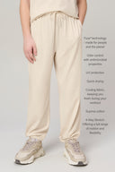 Kid in light beige jogger pants with drawstring waist and elastic cuffs, wearing sneakers.