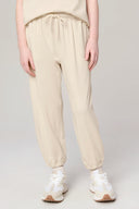 Girl wearing sand-colored jogger pants with elastic waistband and cuffs, white sneakers