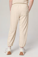 Back view of girl wearing sand-colored kids jogger pants with elastic waistband and sneakers
