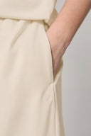 Close-up of sand beige kids jogger pocket with minimalist logo detailing