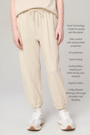Girl wearing beige jogger pants with drawstring waist, white sneakers, and stretchy fabric