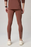 Back view of person wearing brown activewear tights with reflective accents and sneakers