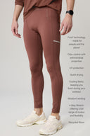 Man wearing sepia brown men's athletic tights with visible anti-odor, UV protection, moisture-wicking features, side pocket, and white sneakers.