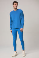 Man wearing cobalt blue activewear tights and long sleeve shirt, standing on neutral background