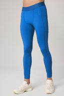 Man wearing cobalt blue athletic tights with pocket detail and white running shoes