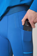 Close-up of cobalt blue athletic tights with phone pocket, hand placing smartphone inside
