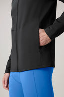 Close-up of a person wearing a charcoal fitted jacket with a zippered pocket and bright blue leggings