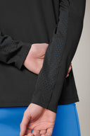 Close-up of black perforated athleisure jacket sleeve with blue leggings