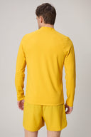 Back view of a man wearing a spicy mustard yellow fitted athletic jacket and shorts