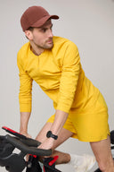 Man wearing spicy mustard yellow athleisure jacket and shorts on indoor bike