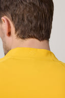 Close-up of a person wearing a spicy mustard yellow fitted athleisure jacket, back view