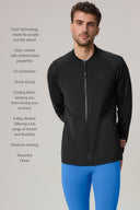 Man wearing a charcoal men's endurance fitted zip jacket with blue athletic leggings, neutral background.